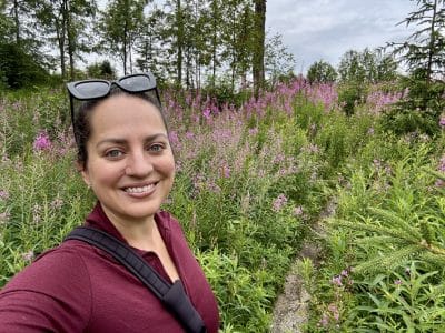 Kate hiking on a trail surrounded by purple wildflowers.