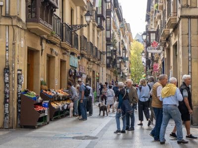 A group of men walking together down a street in the old town, lots of wrought iron balconies on the windows.